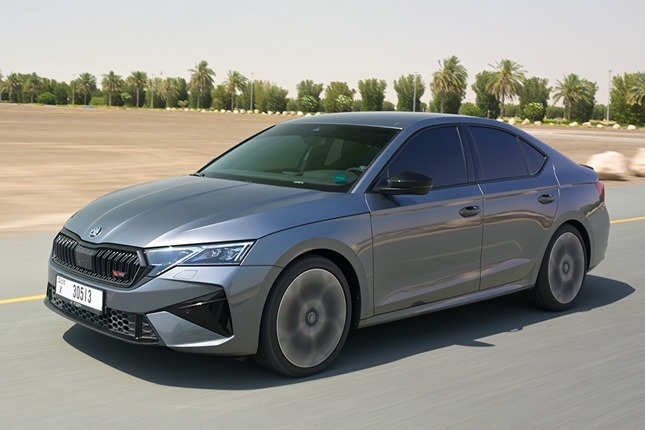 Front three-quarter view of a sleek grey Skoda Octavia luxury sedan driving fast on an asphalt road.