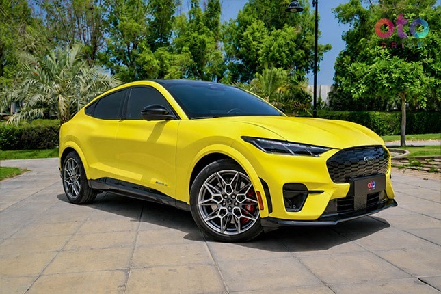 Front three-quarter perspective of a bright yellow Ford Mustang Mach-E electric SUV outdoors.