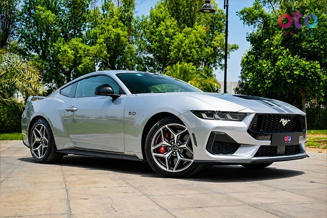 Front three-quarter profile of a silver Ford Mustang GT sports car parked in a paved lot.