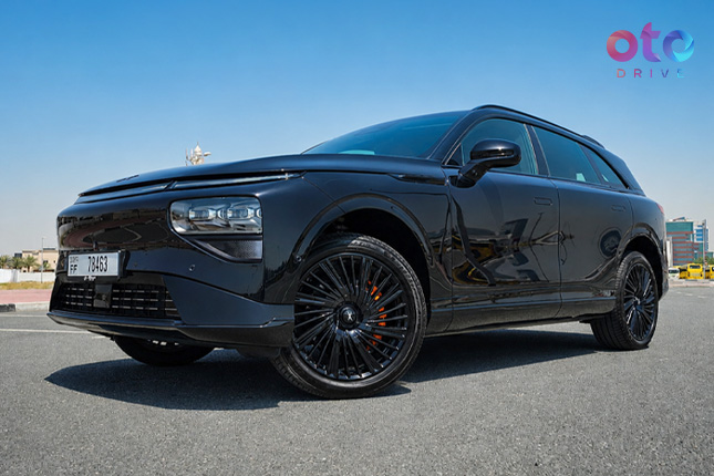 Front three-quarter view of a glossy black electric luxury SUV parked outdoors on an open asphalt road.