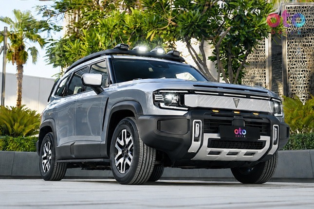 Front three-quarter view of a silver Jetour T2 off-road SUV with roof lights parked in front of trees.